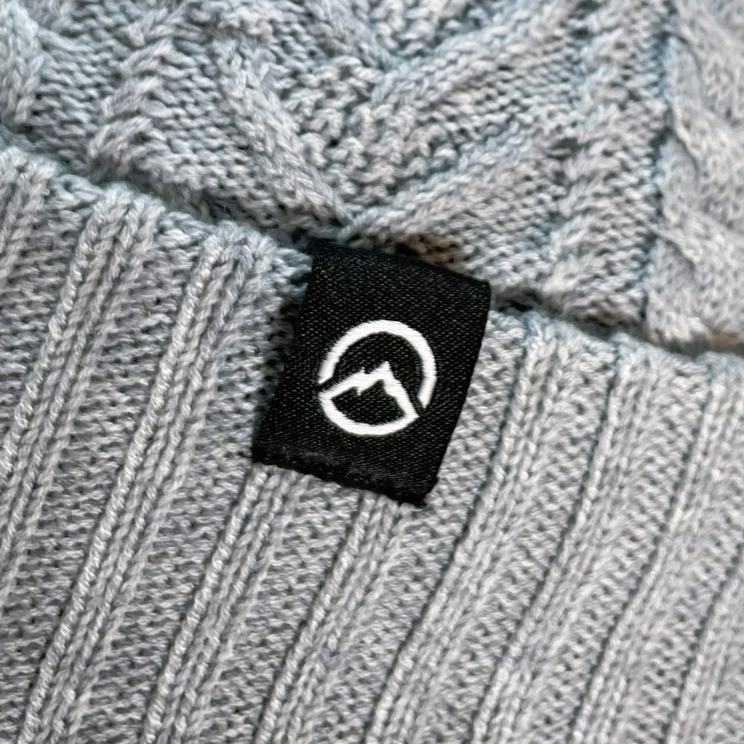 Close up of Domex Logo on Light grey merino blend cable-knit cuffed beanie