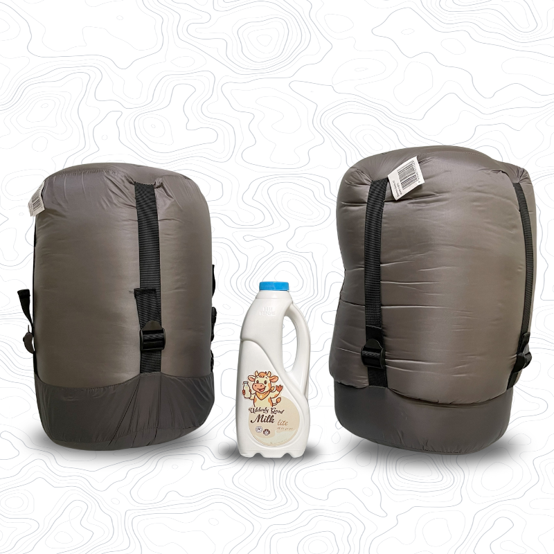 Two Domex Zenith sleeping bags in compression sacks sitting on end on either side of a 1 litre bottle of milk for scale. Standard on the left and XT on the right | GENERAL