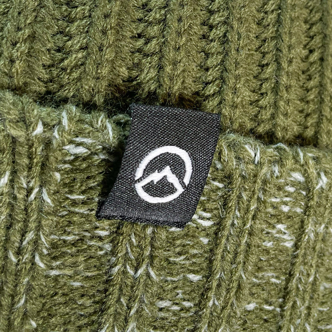 Close up of Domex logo on Front on view of Domex Forest green cuffed chunky knit beanie with pale grey-green gradient accents