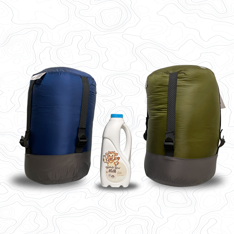 Image of compression sacks on end for Domex Venture Sleeping Bag (blue) and Venture XT Sleeping Bag (green)  with a 1 litre bottle of milk between them for scale | GENERAL