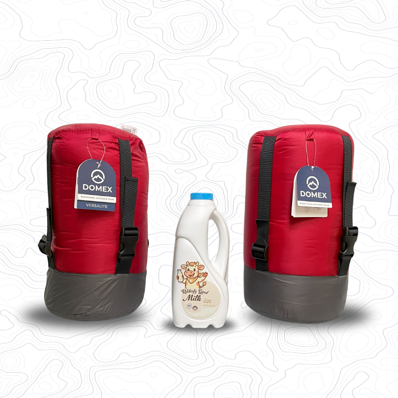 Domex Versalite Sleeping Bags in compession sacks and in red on either side of 1 litre bottle of milk for scale. Left is the standard sized bag, right is the XT | GENERAL