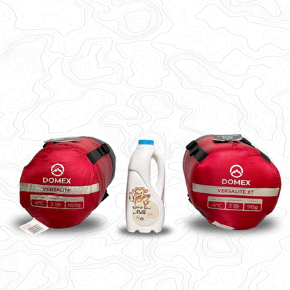 Domex Versalite Sleeping Bags in compession sacks in red on either side of 1 litre bottle of milk for scale. Left is the standard sized bag, right is the XT | GENERAL