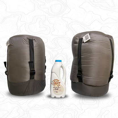 Two Domex Zenith sleeping bags in compression sacks sitting on end on either side of a 1 litre bottle of milk for scale. Standard on the left and XT on the right | GENERAL