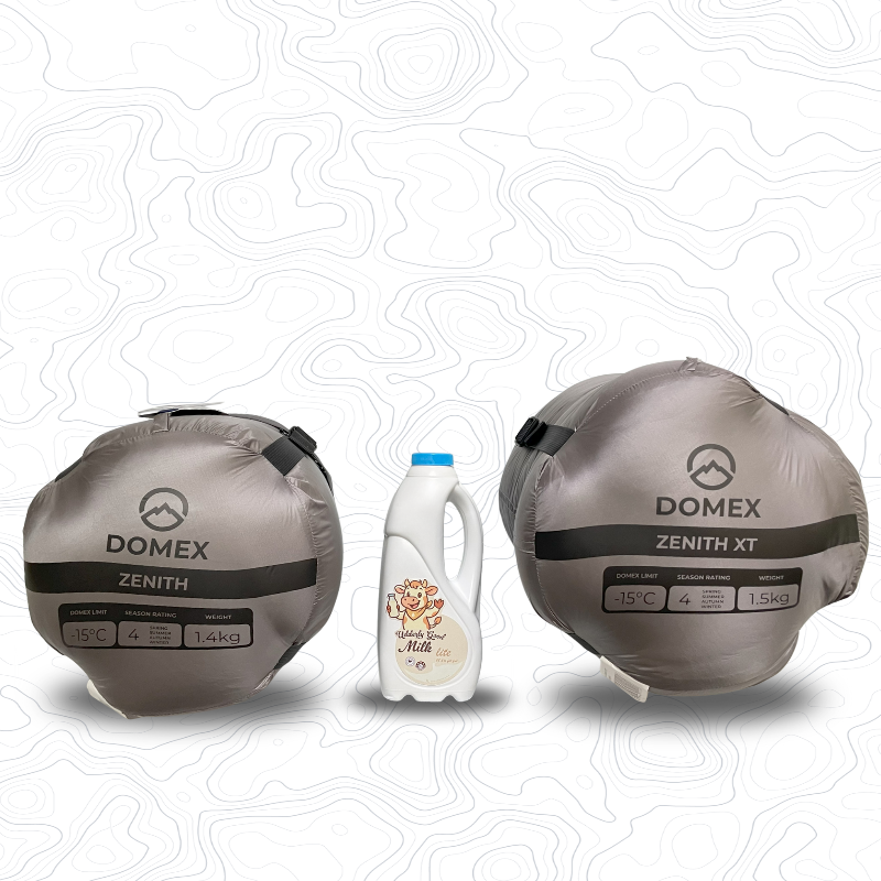 Two Domex Zenith sleeping bags in compression sacks on either side of a 1 litre bottle of milk for scale. Standard on the left (grey, -15C, 1.4kg) XT on the right (grey, -15C, 1.5kg) | GENERAL