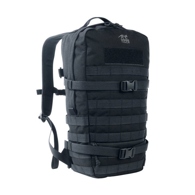 Three quarter front view of Tasmanian Tiger 15 litre daypack with small, flat zipped front pocket. It features two wraparound compression straps and a MOLLE system on the front and sides for individual expansion – Black. Ships Within New Zealand | TT7595.040